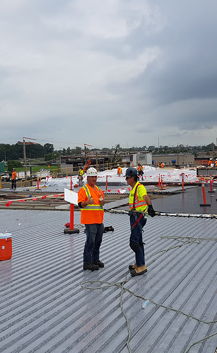 Two Empire Roofing employees holding meeting while working on flat roof